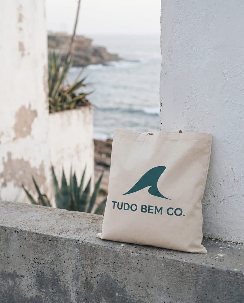 Salt Air Tote in raw canvas resting on a ledge above a cove in Ericeira